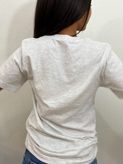 A girl is standing, showing the back of her ash gray shirt.. #color_ash-gray